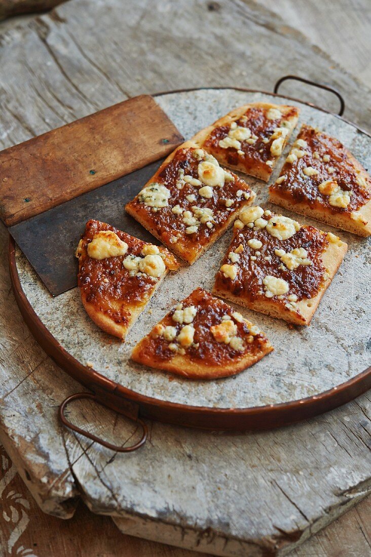 Bacon Jam on grilled flatbread with melted gorgonzola cheese on rustic wooden surface