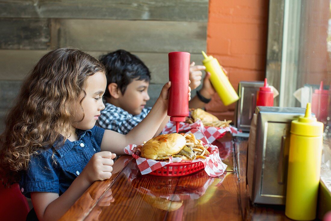 Kinder mit Burger und Pommes in einem Imbiss-Restaurant