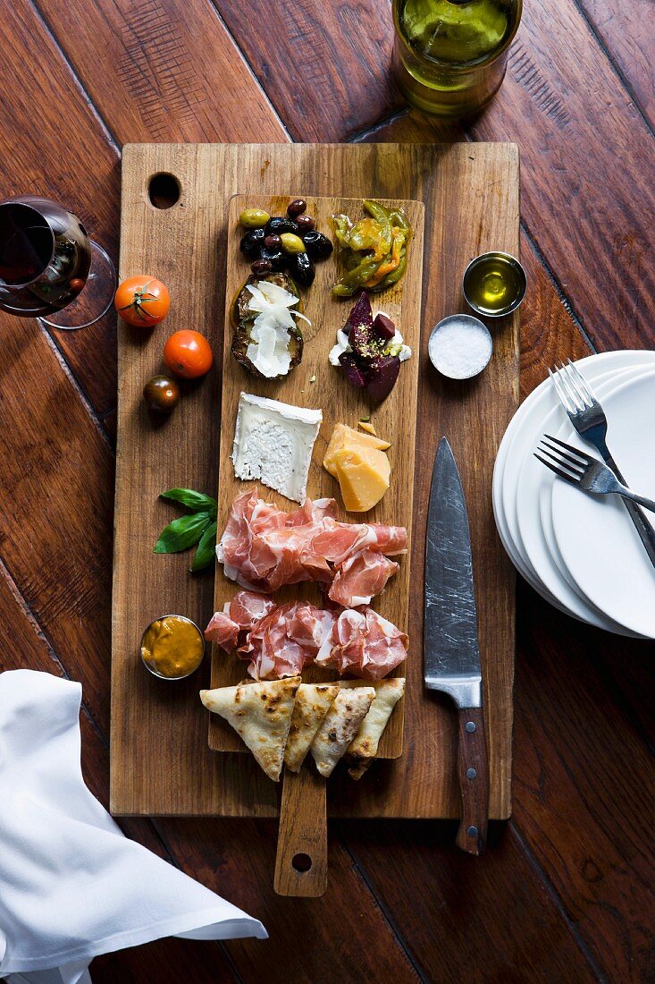 Assorted antipasti on a wooden board (view from above)