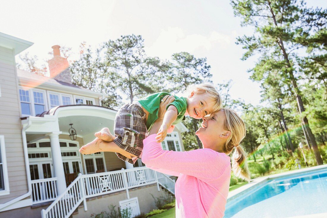 Woman swinging son in air playfully