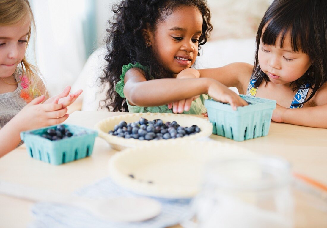 Girls putting blueberries into bowl together