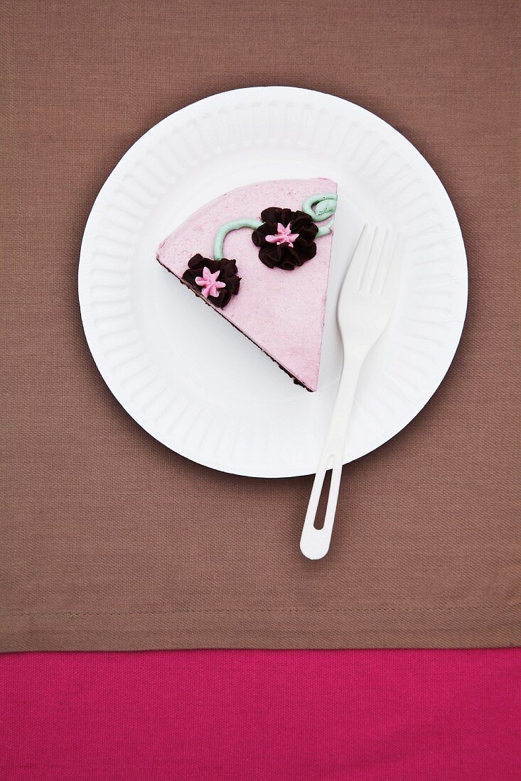 Ein Stück Geburtstagstorte mit rosa Zuckerglasur und Blütendeko