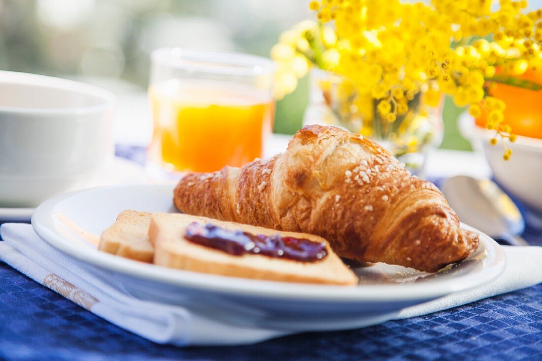 Frühstück mit Croissant, Zwieback und frischem Orangensaft