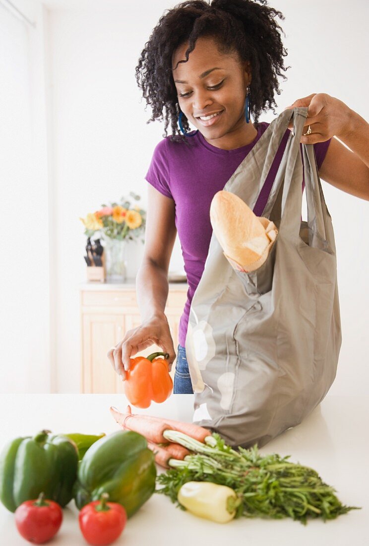 Frau packt Lebensmittel aus auf dem Küchentisch