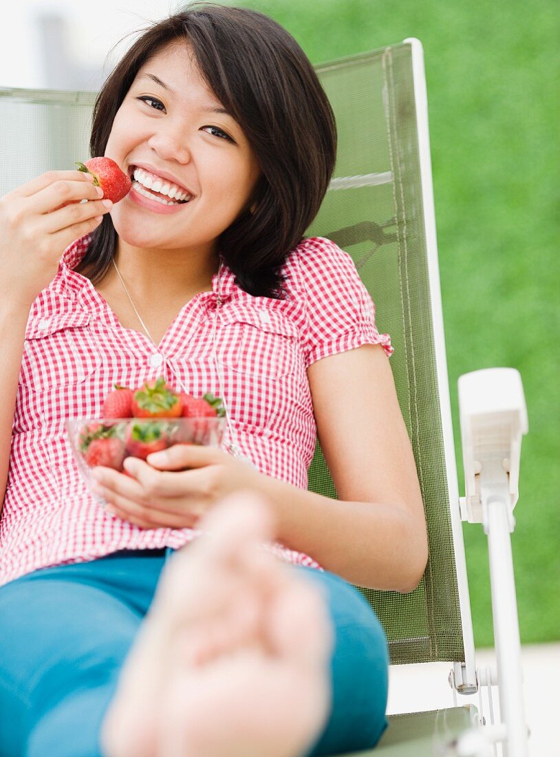 Asian woman eating strawberries