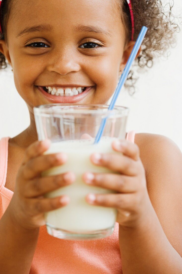 Mädchen hält ein Glas Milch mit Strohhalm