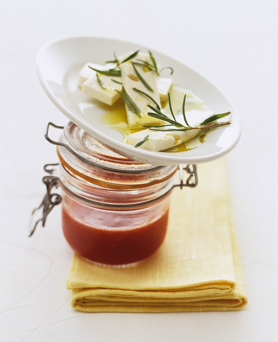 Ewe's cheese with rosemary on top of a jar of tomato sauce