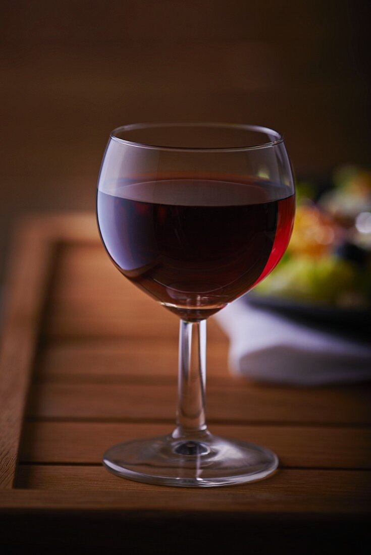 Ein Glas Rotwein auf Holztisch