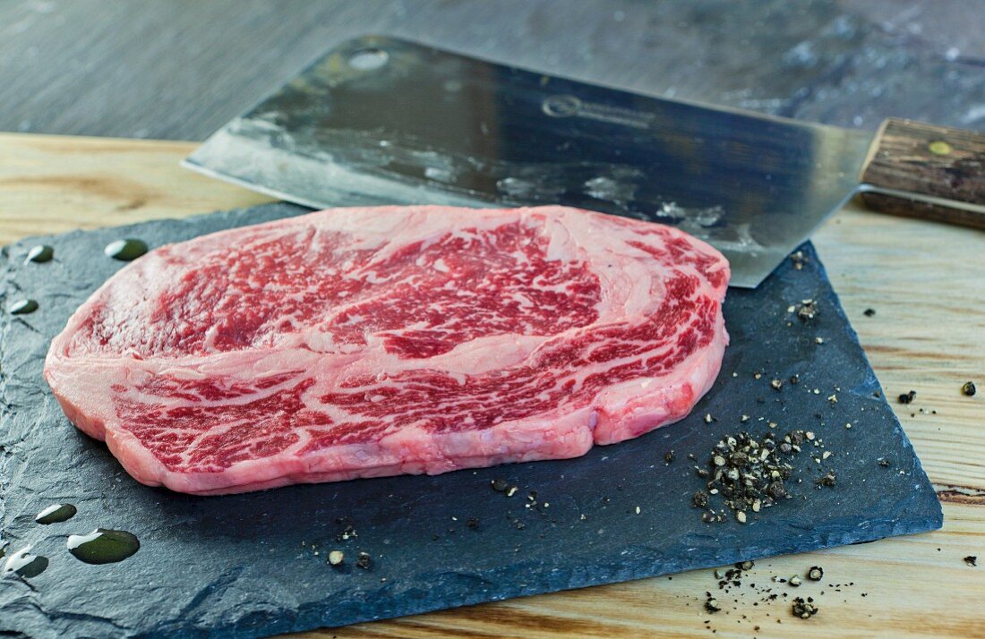 Fresh Wagyu steak on a slate slab with a meat cleaver