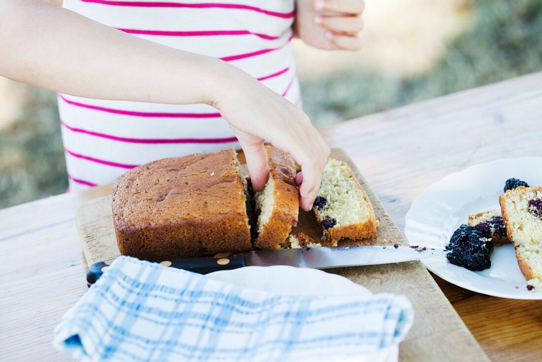 A girl picking up a slice of blackberry cake