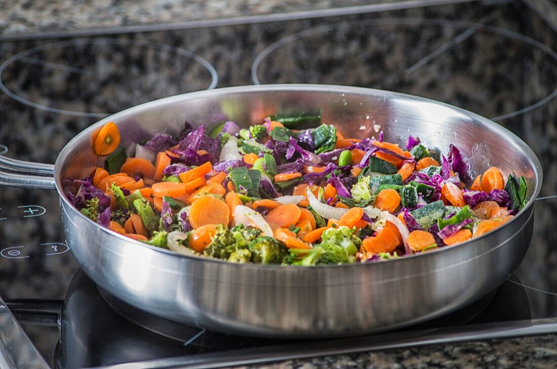 Carrots with red cabbage, broccoli and onions in a frying pan