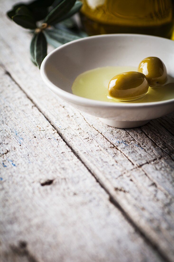 Green olives in a bowl with olive oil