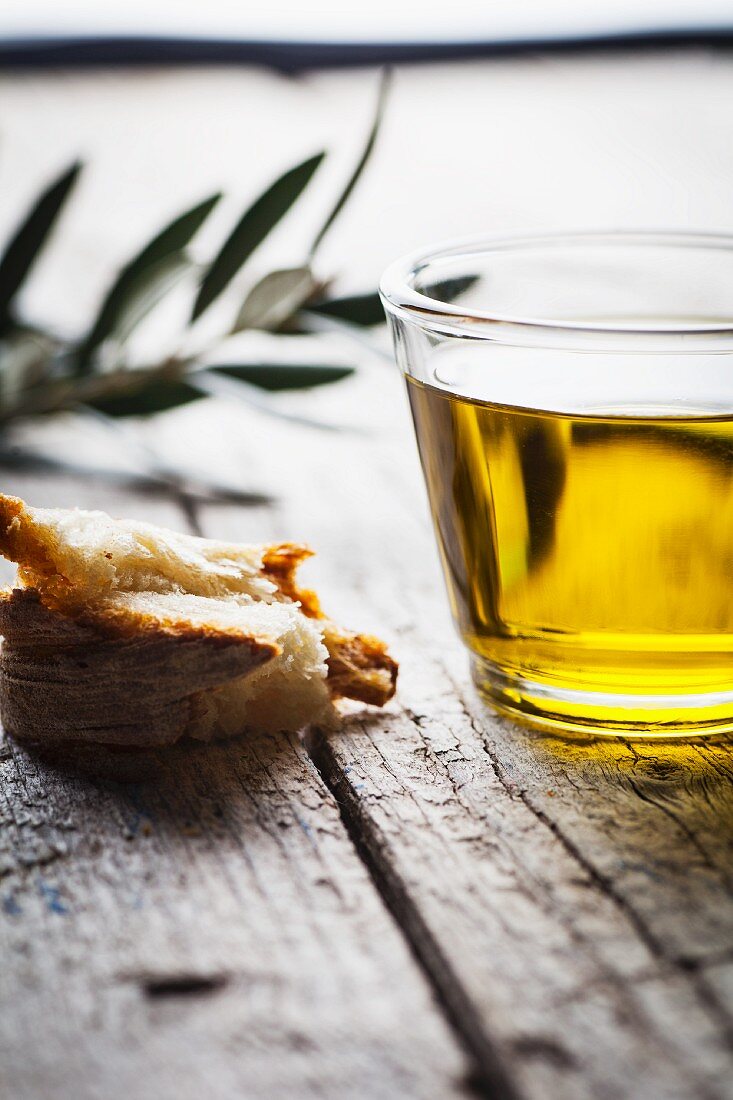 Olive oil, a piece of bread and an olive twig