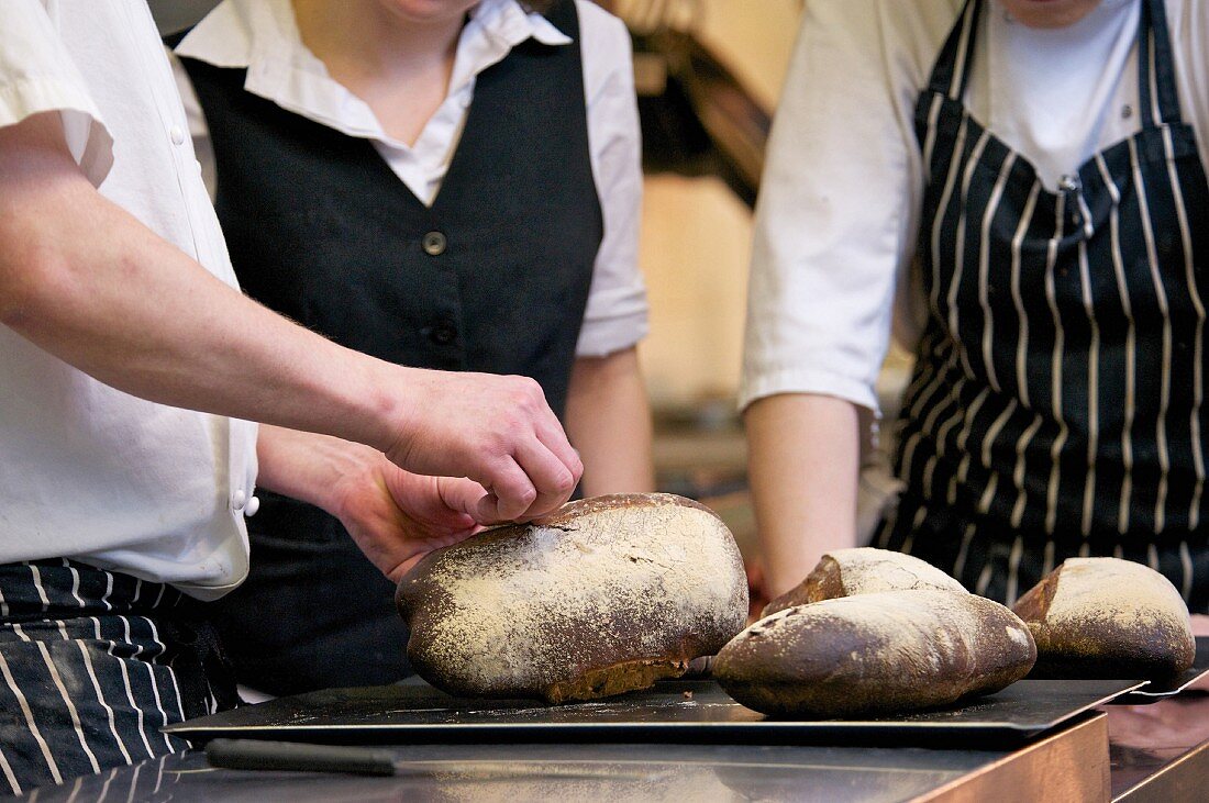Köche und Kellnerin in der Küche mit frisch gebackenem Brot
