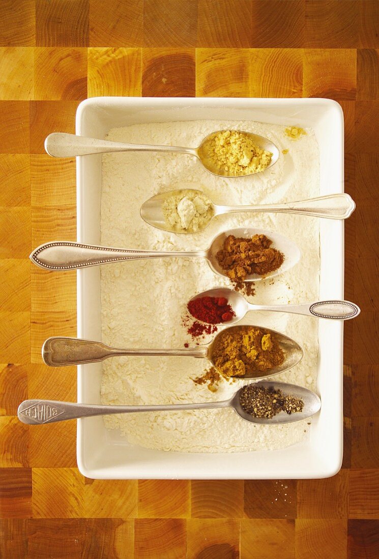 Assorted spices on spoons sitting in flour