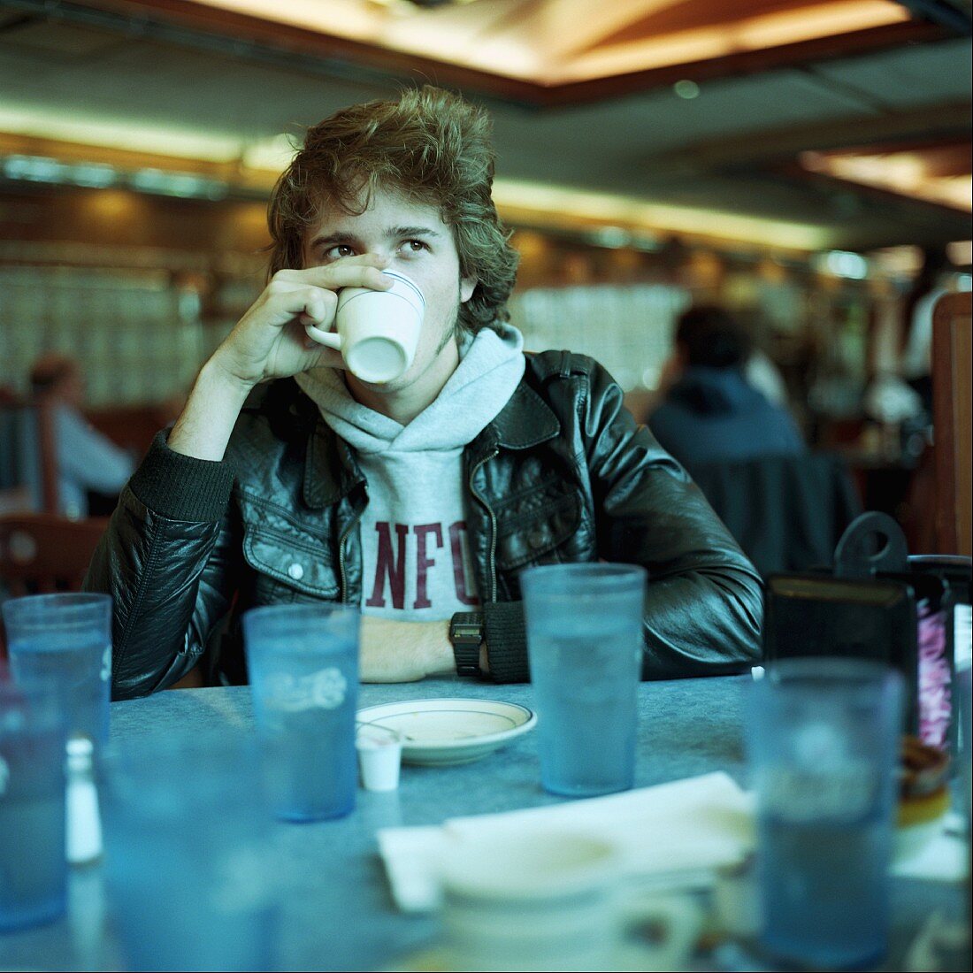 Young man drinking coffee at diner
