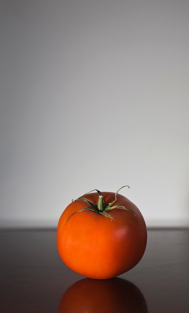 Eine Tomate auf spiegelndem Untergrund