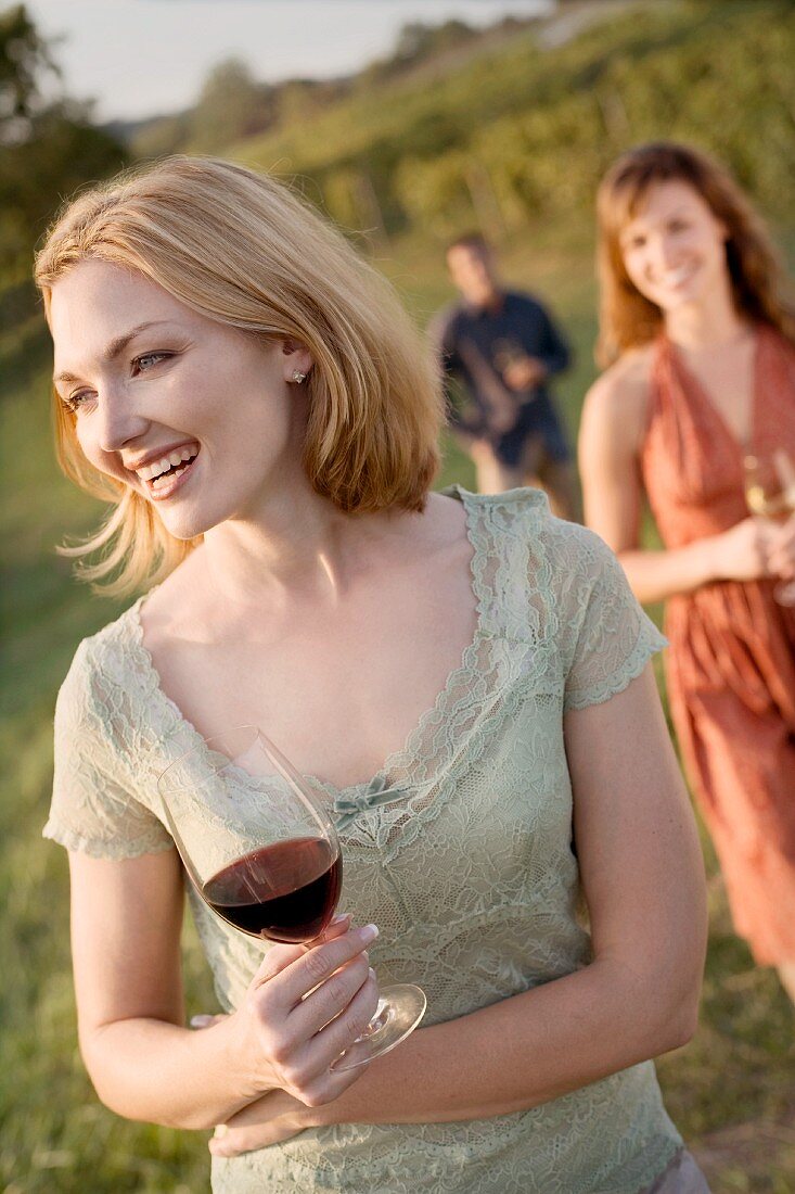 Frau trinkt mit Freunden Wein im Weinberg
