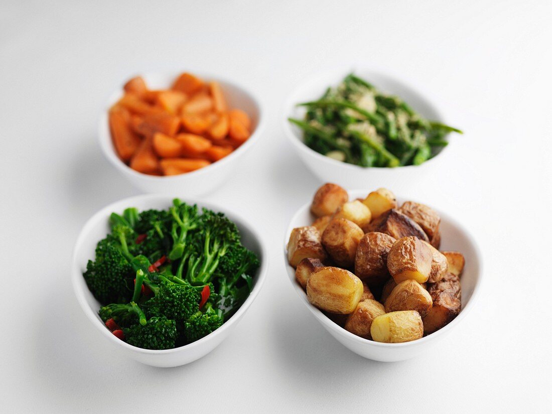 Side dishes of steamed vegetables and roast potatoes.