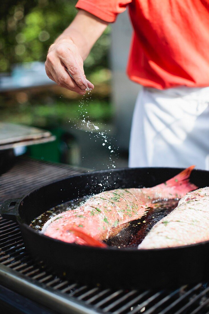 Fish in Cast Iron Pan Being Cooked on Grill