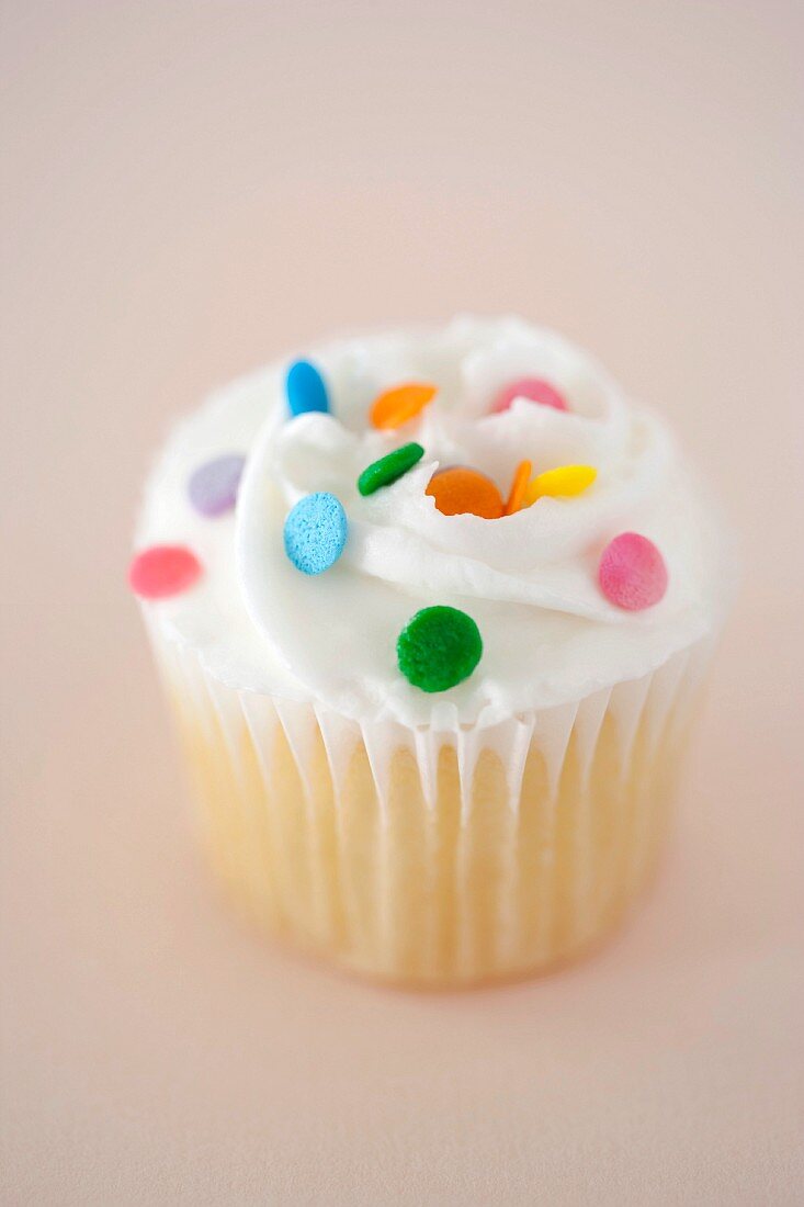Vanilla Cupcake With Colorful Sprinkles on Pink Background
