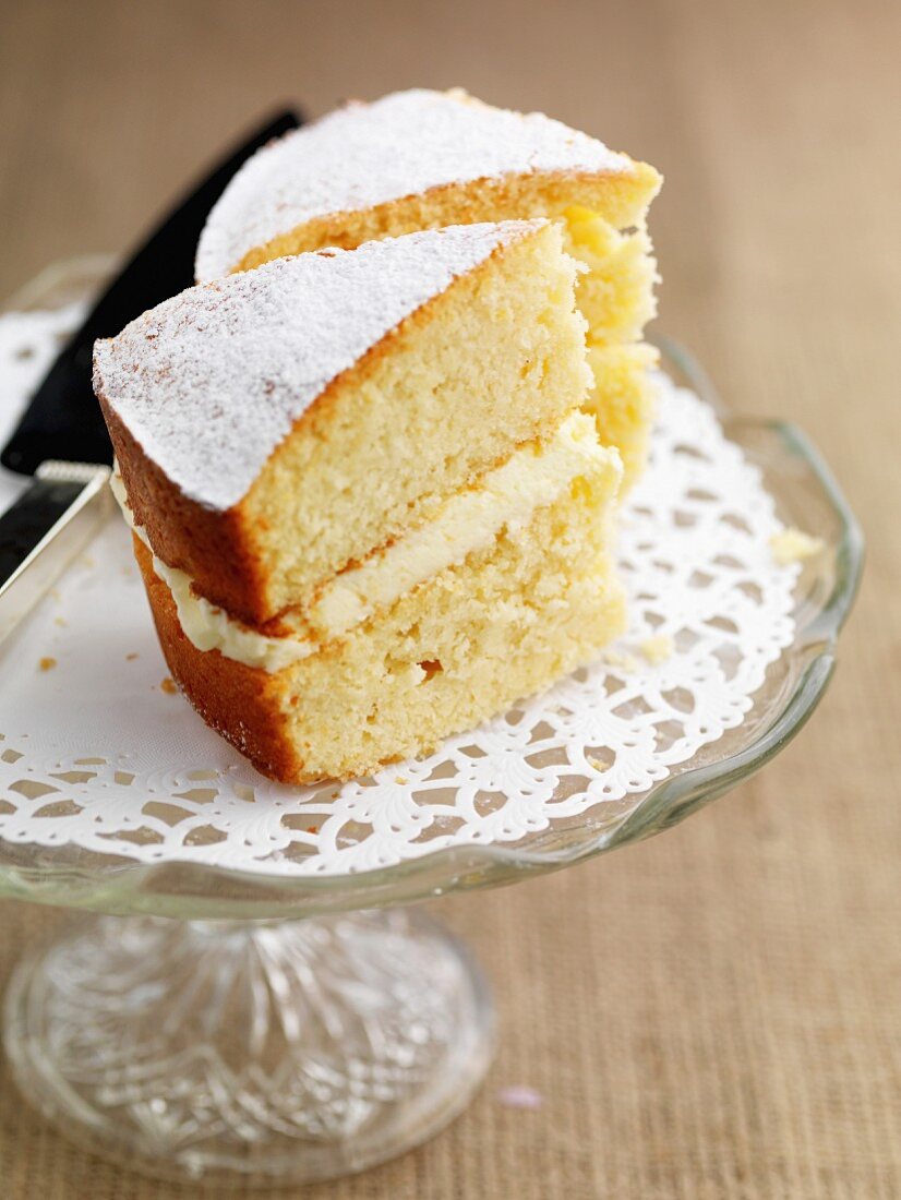 Two slices of gluten-free lemon sponge cake with icing sugar