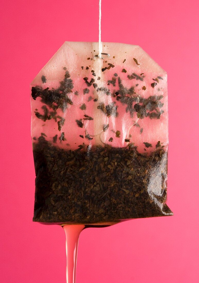 Draining Tea Bag against a pink background