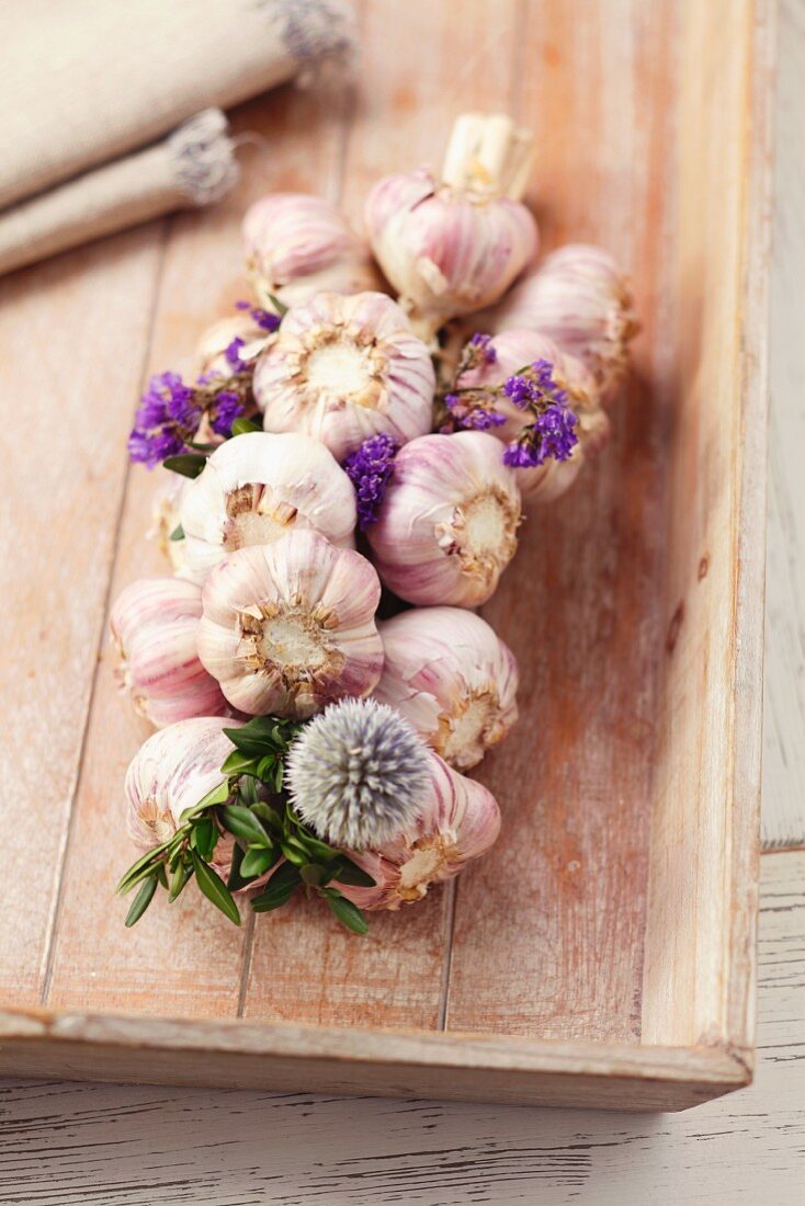 Plaited garlic with flowers on a chopping board