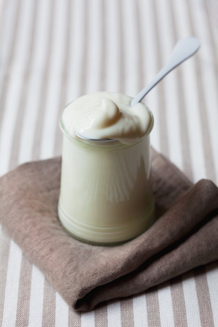 A jar of natural yoghurt on a brown cloth