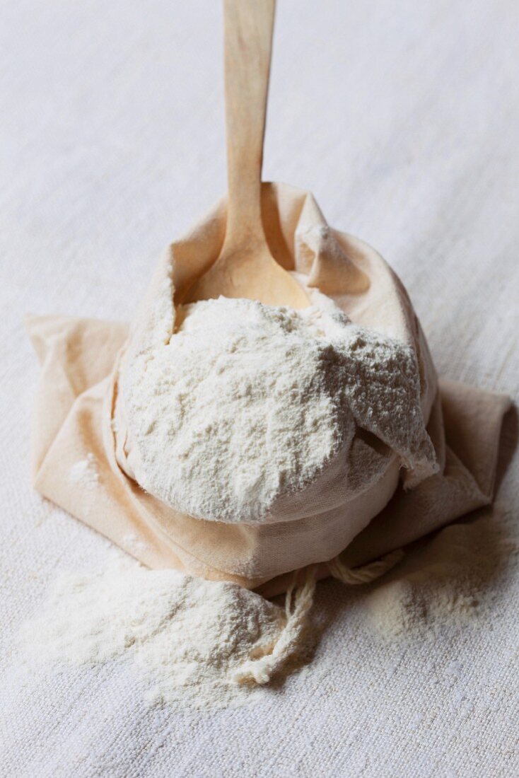 A wooden spoon in a sack of wheat flour