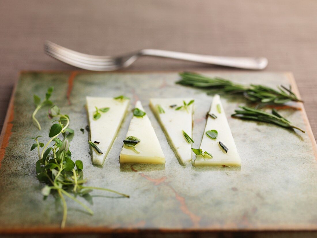 Slices of Manchego cheese with rosemary and oregano
