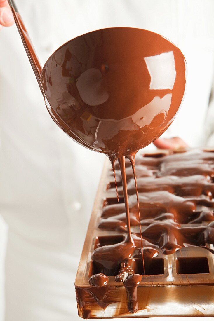 Konditor giesst flüssige Schokolade in eine Form