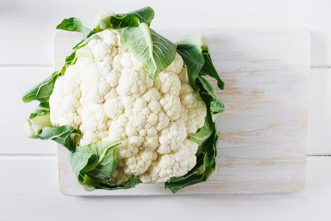 A cauliflower on a chopping board (view from above)