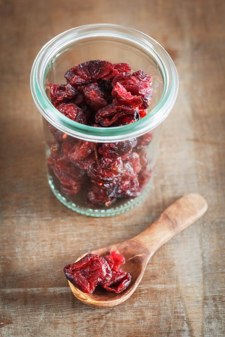 Getrocknete Cranberries im Weckglas und auf Holzlöffel