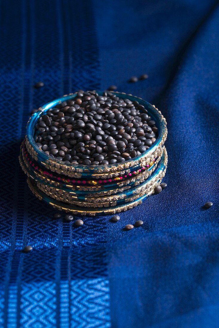 Belugalinsen auf einem blauen Seidensari in einem Ring aus indischen Armreifen