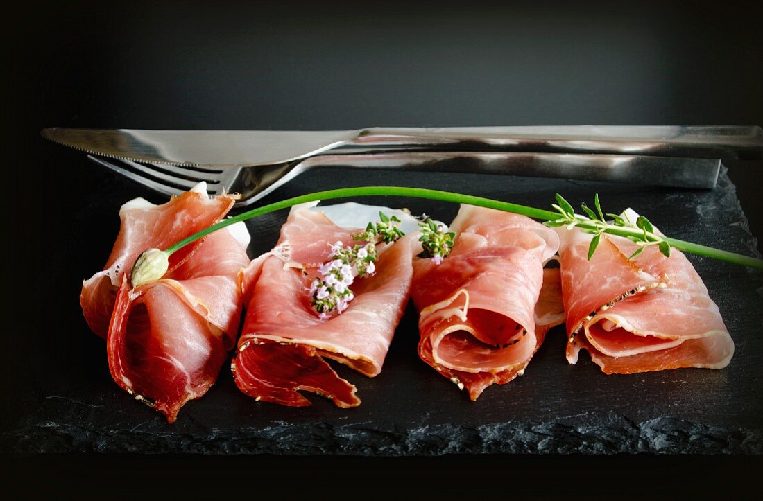 Rolled slices of Black Forest ham on a slate slab with chives