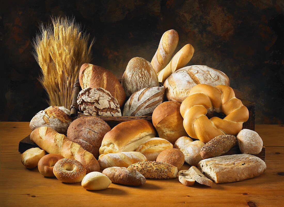 Verschiedene Brote und Brötchen mit Getreideähren auf Holztisch