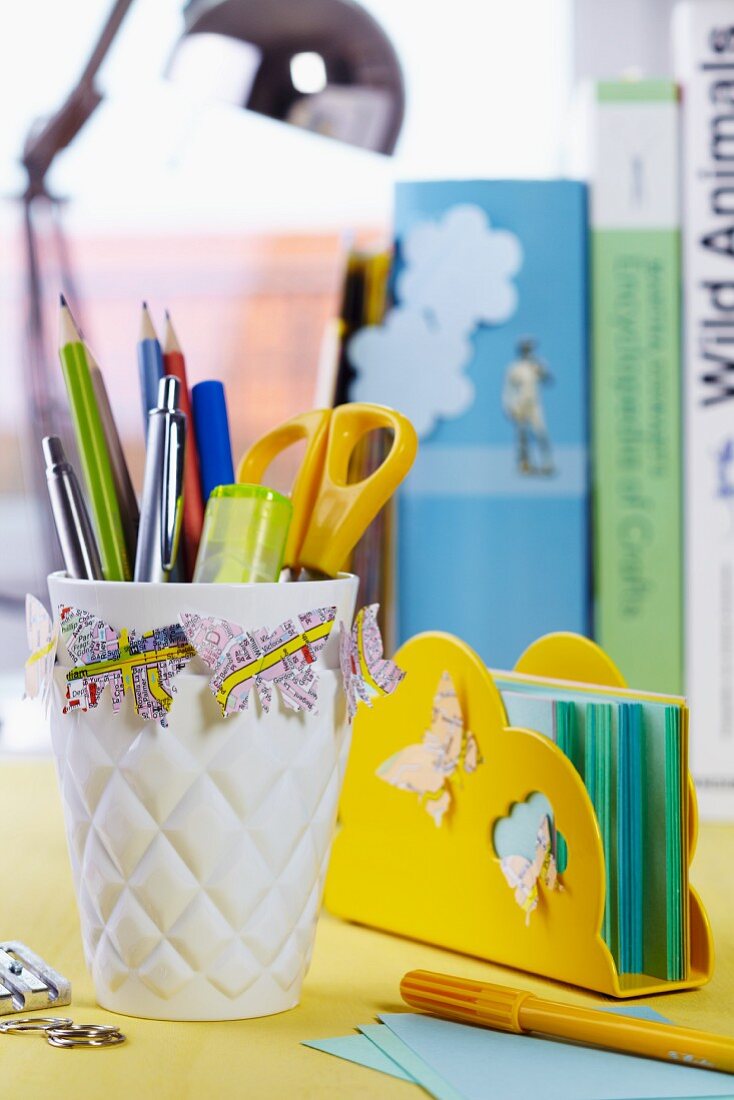 Butterfly shapes punched out of maps decorating writing utensils