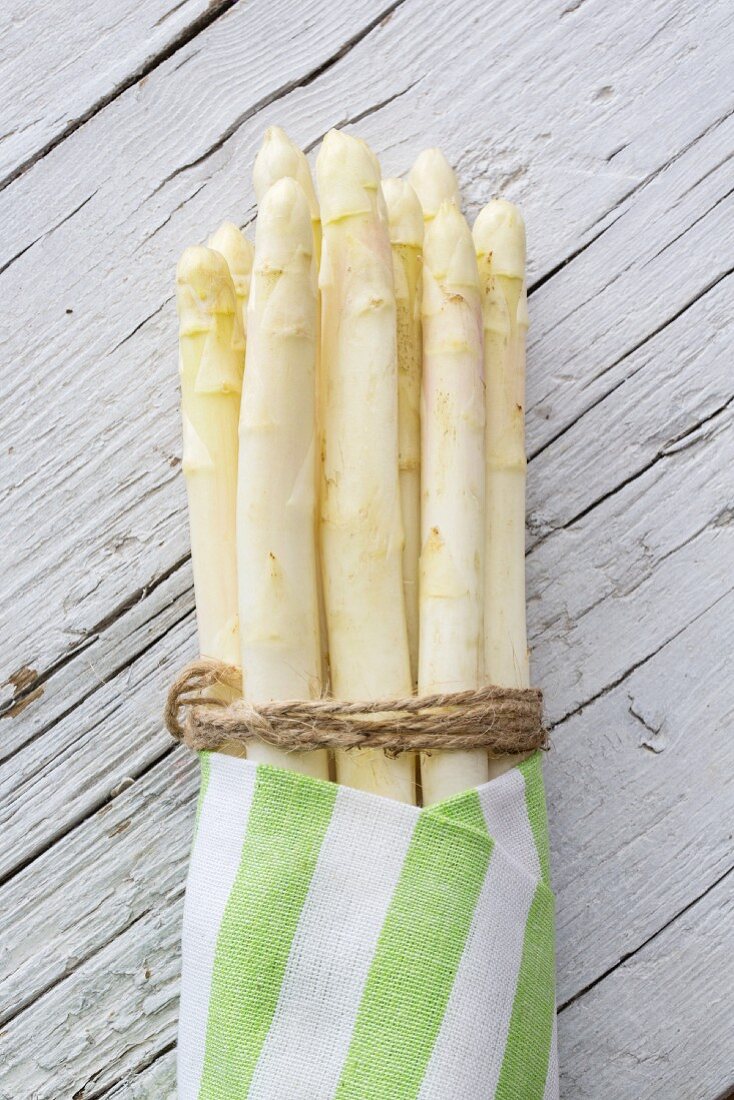 White asparagus, tied in a bundle, in a striped cloth