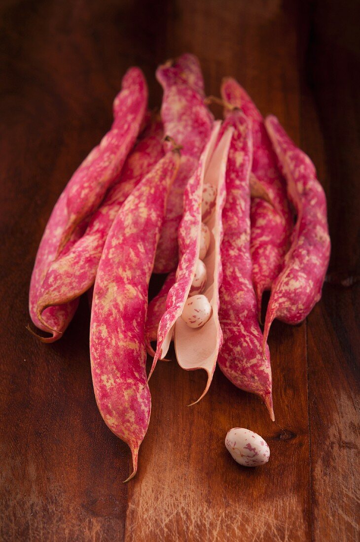 Borlotti pods and beans on wooden cutting board