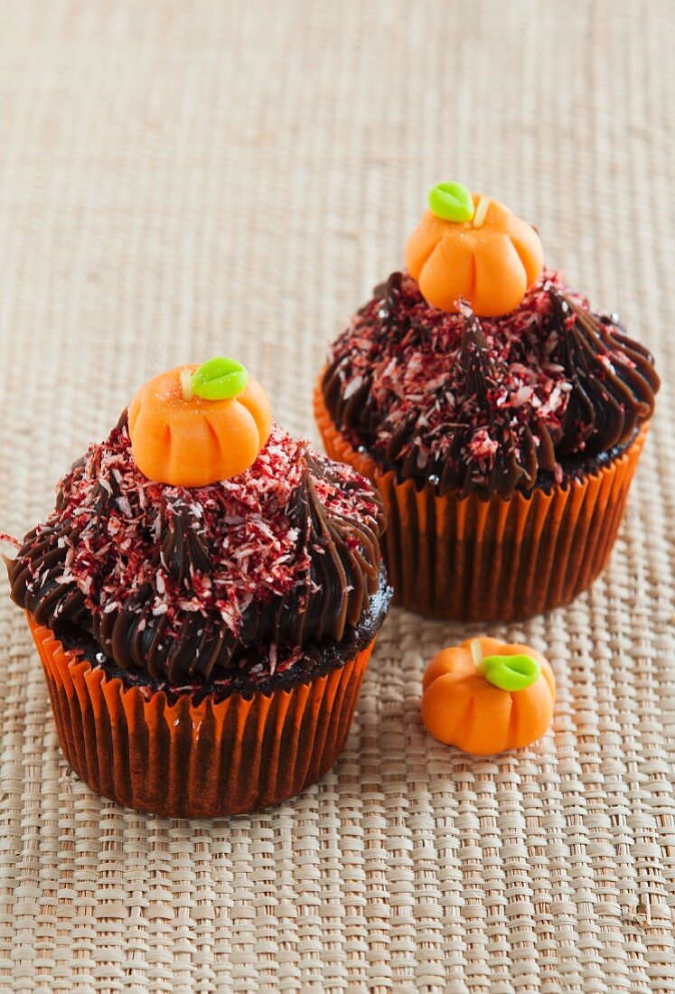 Two chocolate Halloween cupcakes decorated with fondant pumpkins