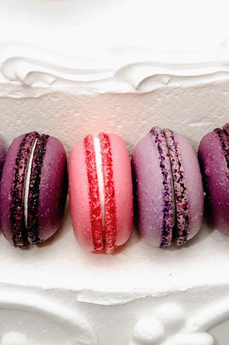 Purple and pink macaroons on a white cream layer cake