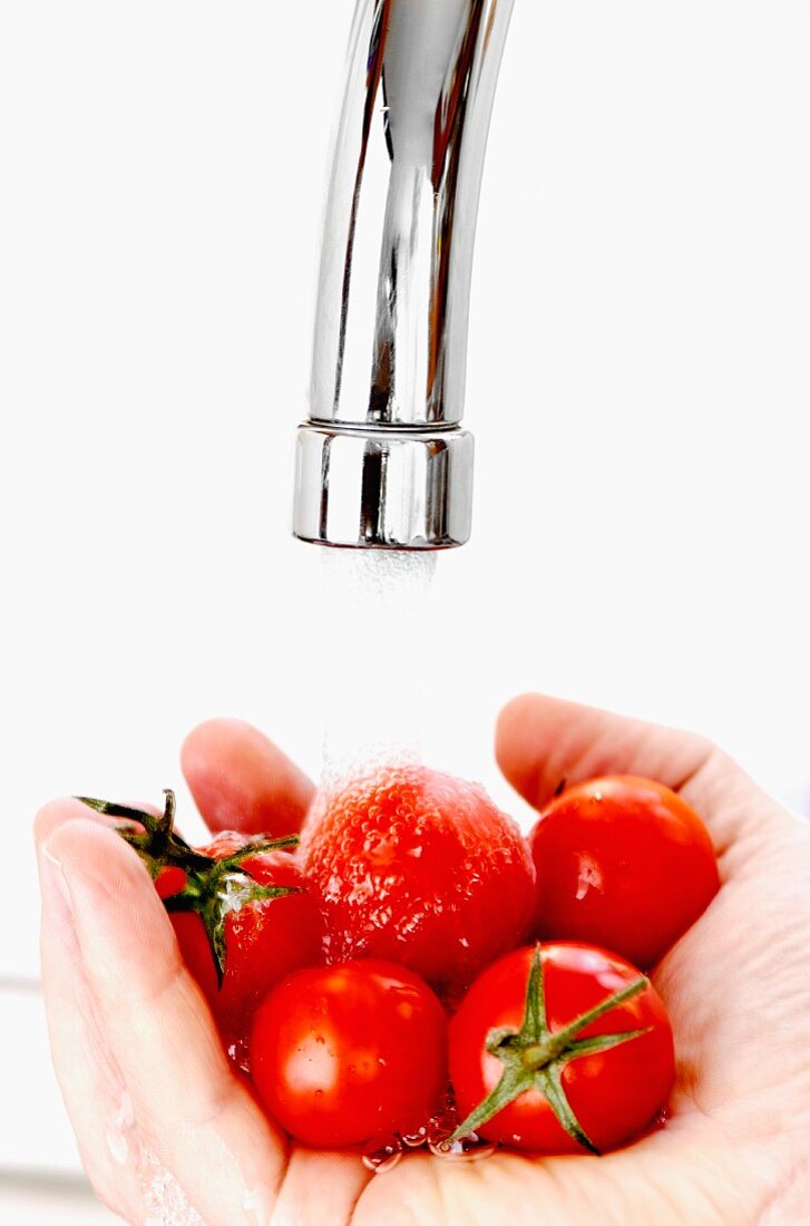 Cherry tomatoes being washed under running water