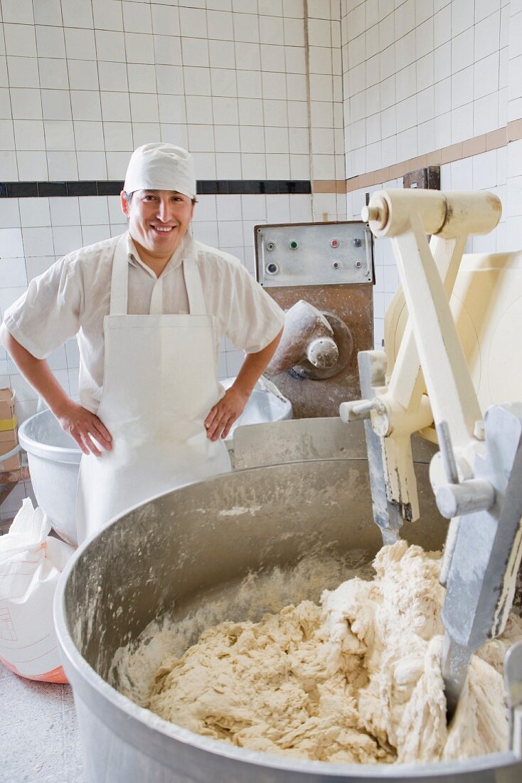 A baker at a kneading machine in a bakery