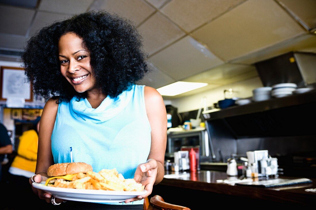 Lächelnde afroamerikanische Frau hält Teller mit Burger