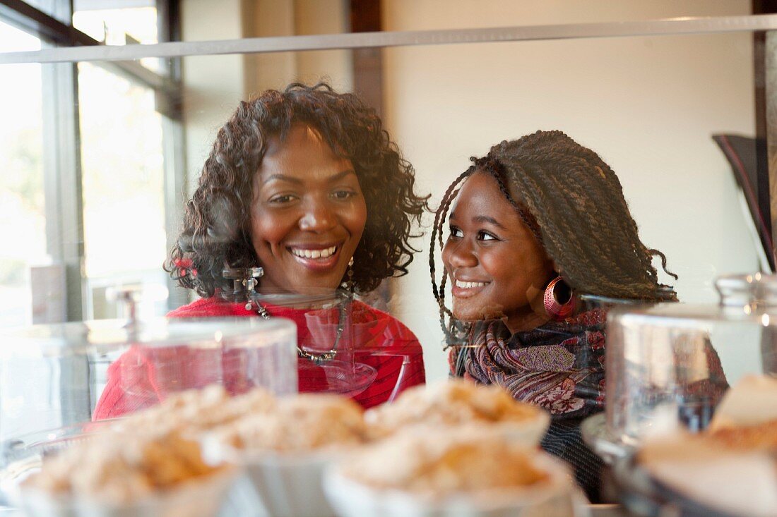 A dark-skinned mother and her adult daughter in front of a display in a cafe