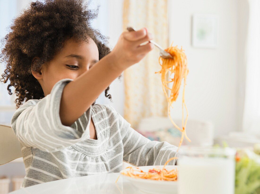 An African-American boy eating spaghetti