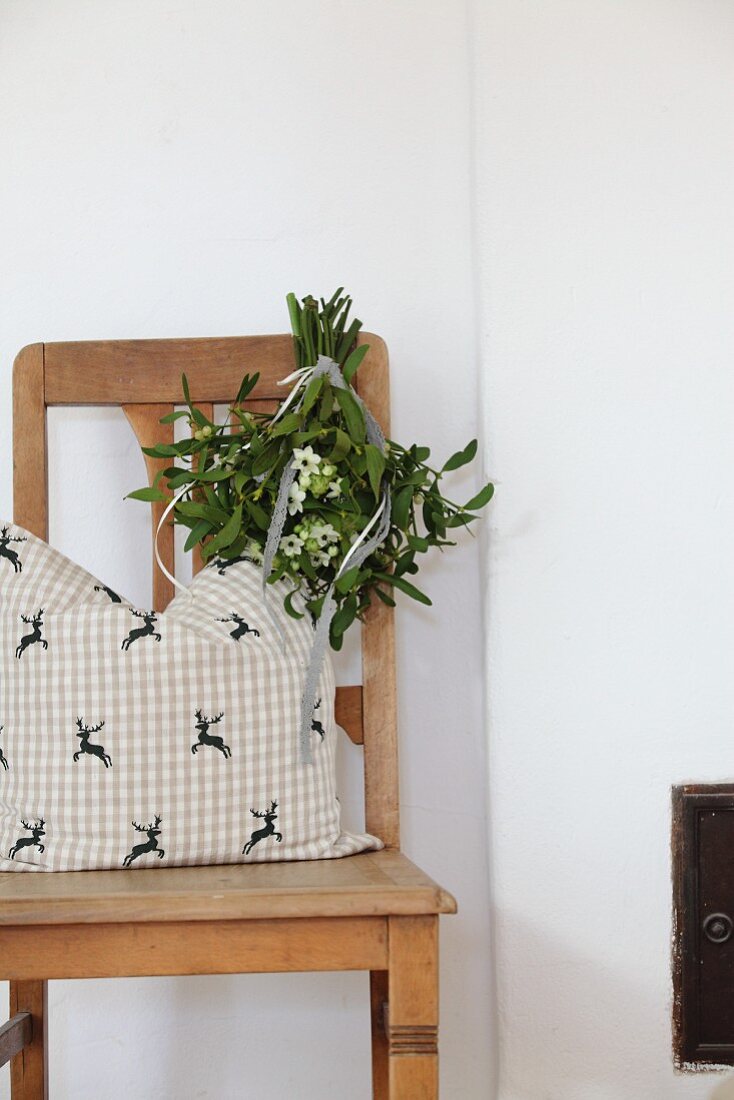 Old wooden chair with cushion and posy of mistletoe and Star-of-Bethlehem flowers hanging from backrest