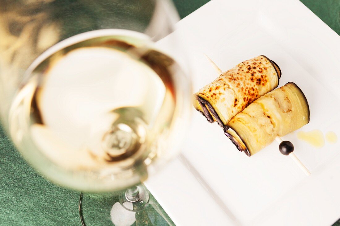 Fried aubergine rolls and a glass of white wine