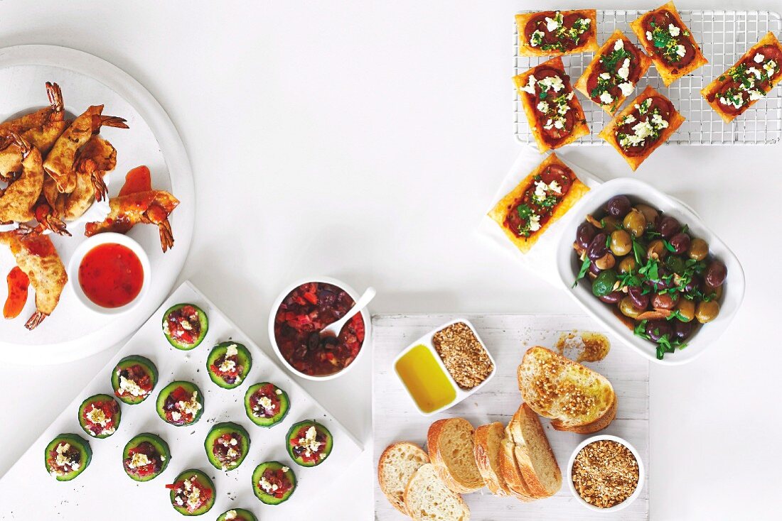 Verschiedenes Fingerfood: Garnelen, Gurkentaler, Knoblauch-Oliven und Dukkah mit Olivenöl und knusprigem Brot